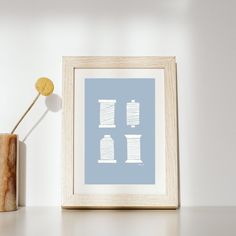 a white frame with a blue print on it next to a vase