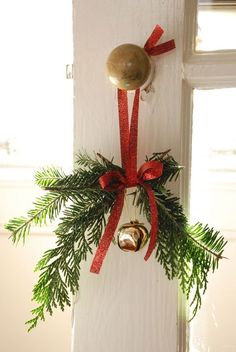 a bell hanging from the side of a door with a red ribbon around it and a bow