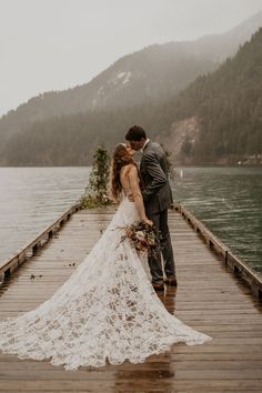 a bride and groom kissing on a dock