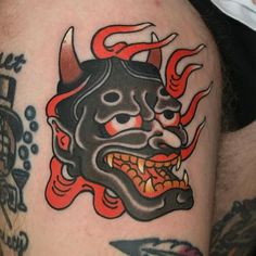 a man with a tattoo on his arm that has a demon head and flames coming out of it