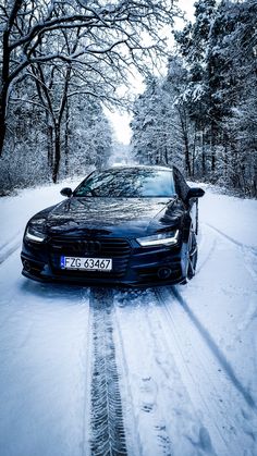 a car parked on the side of a snow covered road in front of some trees