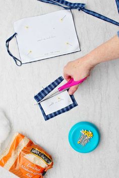 someone is cutting paper with scissors and some other crafting supplies on the table next to them