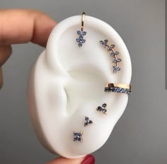 a person holding an earring with blue and white butterflies attached to the back of it