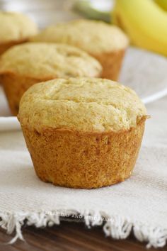 three banana muffins sitting on top of a white plate next to some bananas