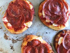 four pepperoni pizzas sitting on top of a pan