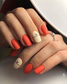 a woman's hand with orange and white nail polish