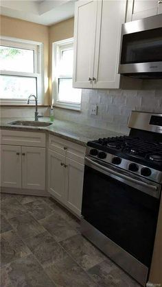 an empty kitchen with white cabinets and stainless steel stove top oven, dishwasher and microwave