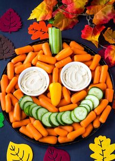 a plate with carrots, cucumbers and dip in the shape of a face