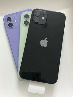 three iphones are sitting side by side on a white surface and one is blue, the other is green