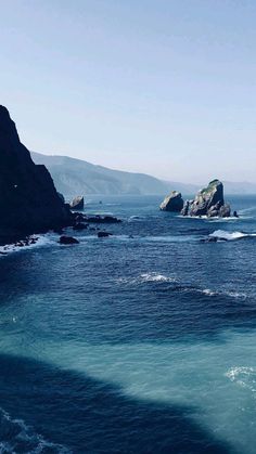 the water is very blue and there are two large rocks in the distance