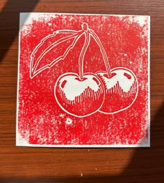 two cherries with an umbrella on top of a piece of paper that has been stenciled