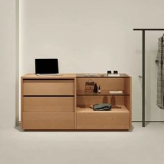 a wooden cabinet with drawers and a laptop on it in front of a white wall