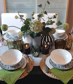 the table is set with plates, silverware and flowers in black and white vases