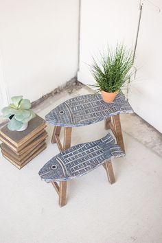 two fish shaped tables sitting next to each other on top of a white floor covered in books