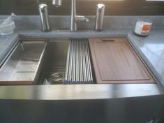 a stainless steel kitchen sink with wooden cutting boards