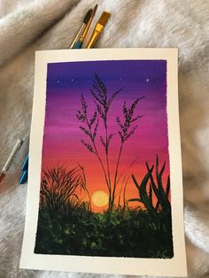 a painting of a sunset with grass in the foreground and paintbrushes next to it