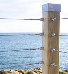 a wooden post sitting on the side of a cliff next to the ocean with water in the background