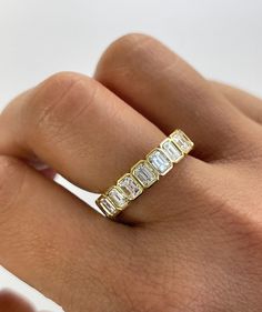 a woman's hand wearing a gold ring with five baguettes on it