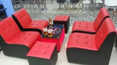 red and black couches are arranged in a room with tables, chairs, and stools