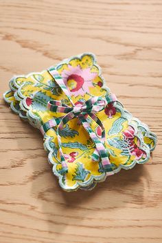 a yellow and pink flowered paper napkin on a wooden table with a bow tied around it