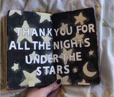 a hand holding an open book that says thank you for all the nights under the stars