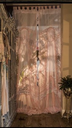 an open window with sheer curtains in front of it and a potted plant next to it