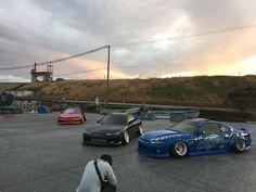 three cars parked in a parking lot next to each other with the sun setting behind them