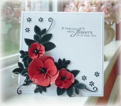 a white card with red flowers and black leaves on it's side, in front of a window