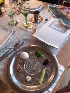 a silver plate with food on it sitting on a table next to wine glasses and utensils