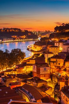 the city is lit up at night with lights on buildings and water in the background