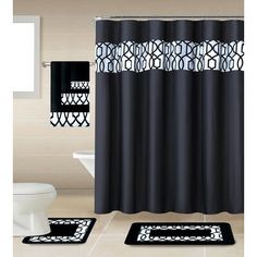 a black and white shower curtain next to a toilet in a bathroom with two rugs on the floor