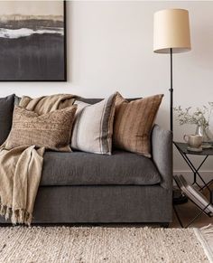 a living room with a couch, lamp and pictures hanging on the wall above it