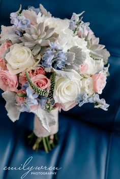 a bridal bouquet sitting on top of a blue leather chair with white and pink flowers