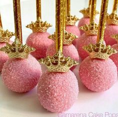 pink cake pops with gold crowns on top are ready to be served for the guests