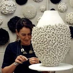 a woman is working on a large vase