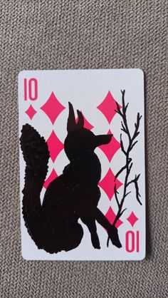 a playing card with a black squirrel on it's back and pink squares in the background