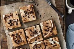 chocolate squares with peanut butter frosting on a wooden table next to a cup of coffee