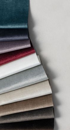 a stack of different colored sheets on top of each other in various sizes and colors