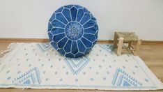 a blue and white round pillow sitting on top of a rug next to a wooden chair