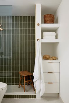 a bathroom with green tiled walls and flooring, including a white toilet sitting next to a walk in shower