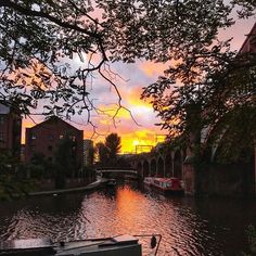 a boat is docked on the side of a river as the sun sets in the background