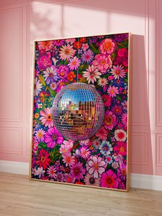 a mirror ball hanging from the side of a pink wall with flowers on it in front of a wooden floor