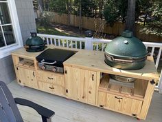 a big green egg sitting on top of a wooden table next to a bbq