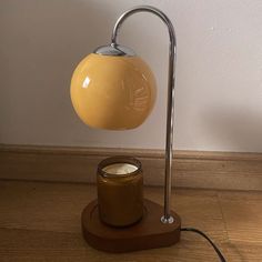 a table lamp that is on top of a wooden base with a jar underneath it