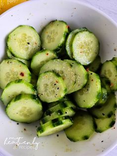 a white bowl filled with sliced cucumbers next to an orange and lemon slice