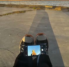 someone taking a selfie with their cell phone in front of the ocean and sunset