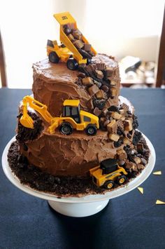 a three tiered chocolate cake with construction trucks on top