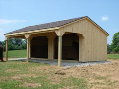 a horse is standing in the grass next to a building that has two stalls on it