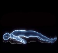 a woman is laying down in the dark with her body glowing blue and white,