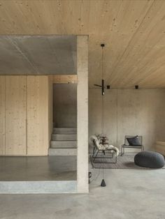 an empty living room with concrete walls and stairs leading up to the second floor area